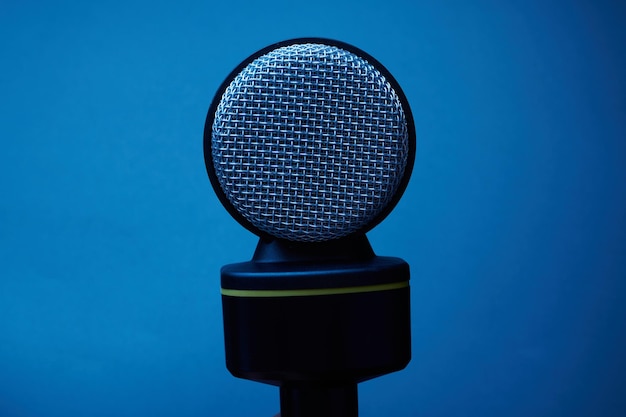 Black microphone isolated on blue background close up