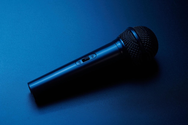 Black microphone isolated on blue background close up