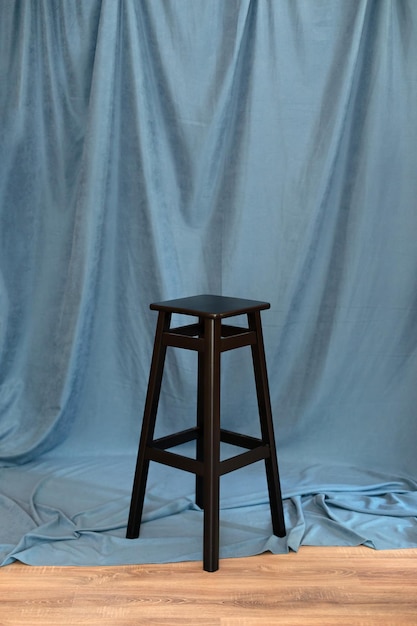 black minimalist wooden chair against blue background.