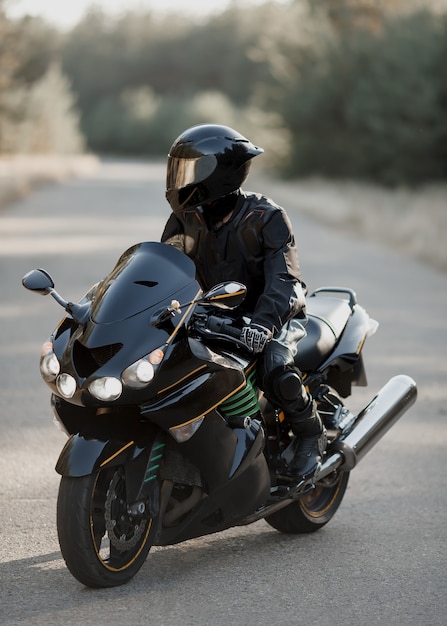 Black motorcycle driver in helmet on road