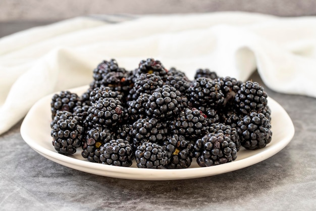 Black mulberry on dark background Fresh and juicy black mulberry on the plate Organic food close up