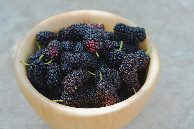 The Black mulberry in a wooden cup is a fruit with a sweet and sour taste Health benefits