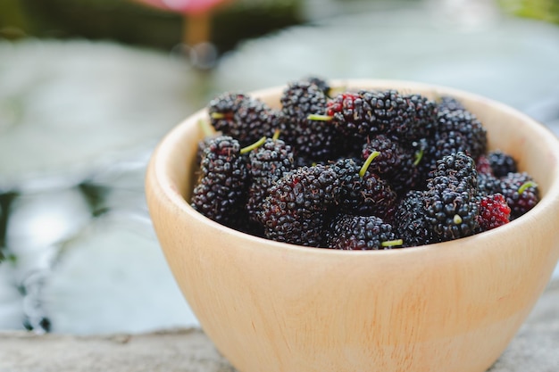 Black mulberry in wooden cup It is a fruit of the berry family that has health benefits