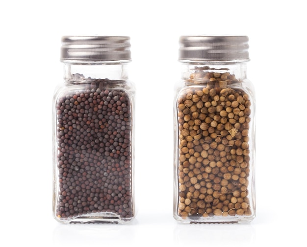 Black mustard bottle and coriander seeds isolated on white background