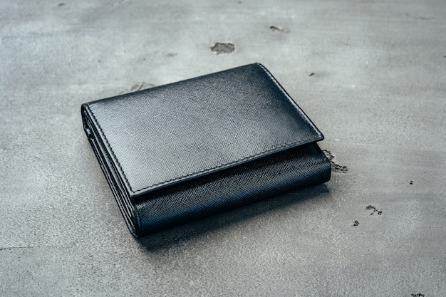 Black new leather wallet on grey concrete background