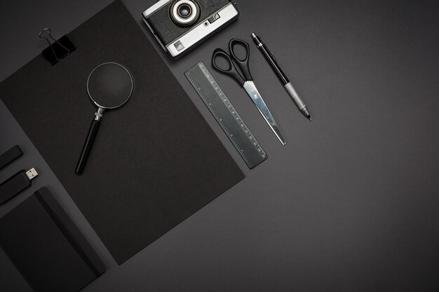 Black objects from the office on a dark gray background. Work and creativity. Social media concept hero header image. Top view. Still life. Copy space