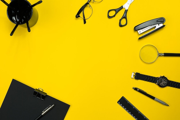 Black objects from the office on a yellow background. Work and creativity. Social media concept hero header image. Top view. Still life. Copy space