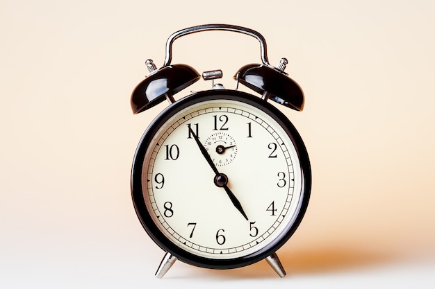 Black old fashioned alarm clock on beige background.