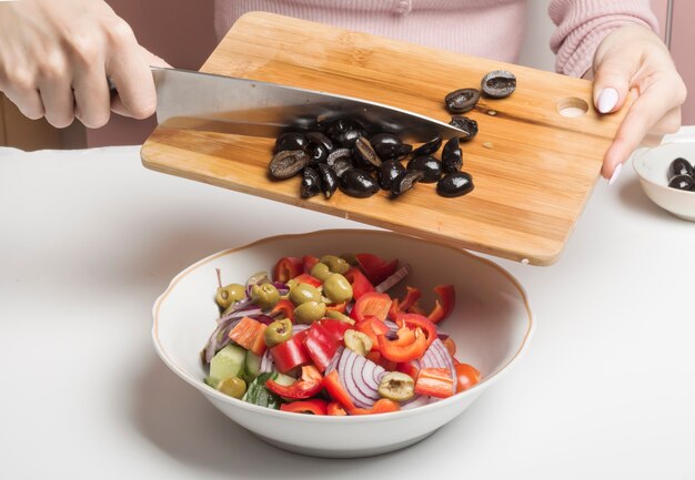 Black olives on a cutting Board are added to the salad.