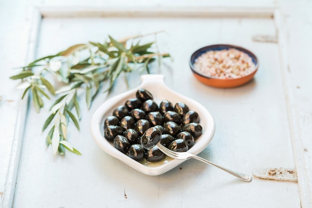 Black olives in white ceramic plate on board