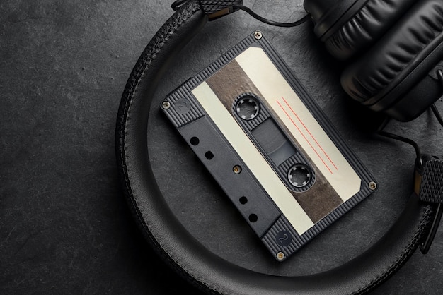 Black onear headphones and audio tape compact cassette on slate background