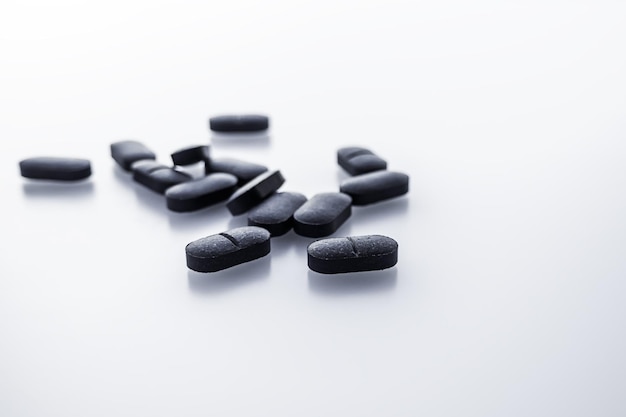 black oval pills on a white table. dietary supplements, drugs concept