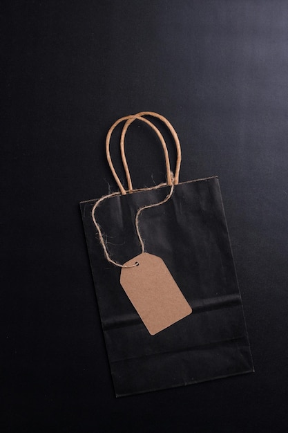 Black paper bag with blank hang tag or price tag for mock up on black background. Black friday sale.