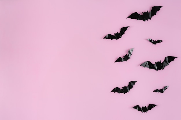 Black paper bats flying over pink