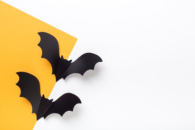 Black paper bats on yellow and white background. Halloween greeting card with copy space for your text - Image