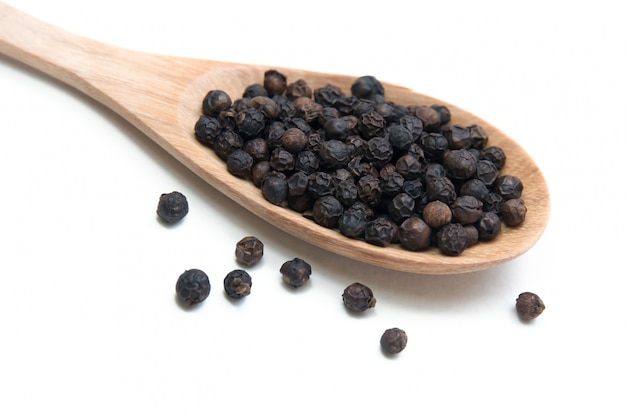 Black pepper grains on wooden spoon.