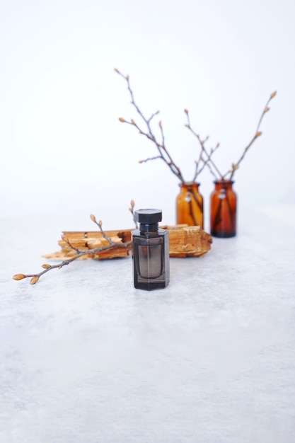 black perfume bottle on a background of wooden bark and branches