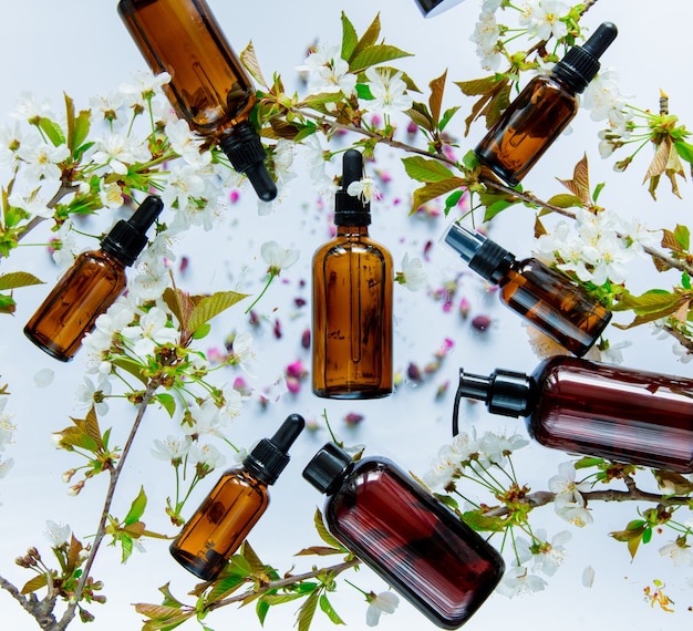 Black perfume bottles and cherry flowers around on white surface