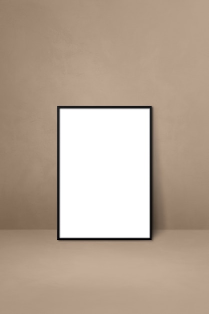 Black picture frame leaning on a beige wall. Blank mockup template