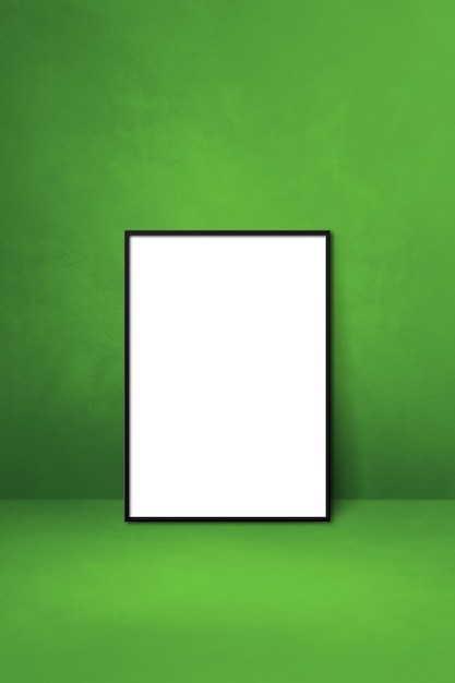 Black picture frame leaning on a green wall. Blank mockup template