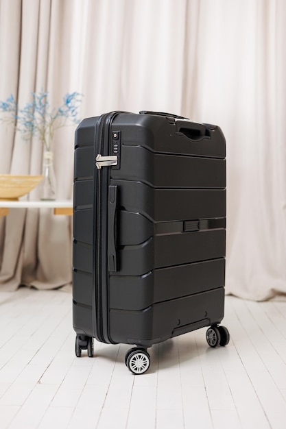 Black plastic strong suitcase for carrying luggage on a white background A bright suitcase for travel