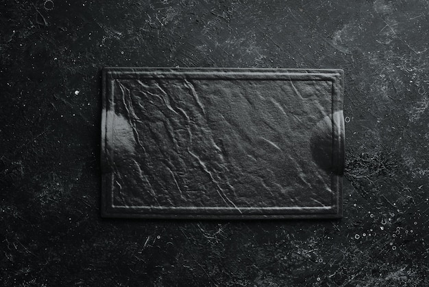 Photo black plate on a black stone background top view free space for your text