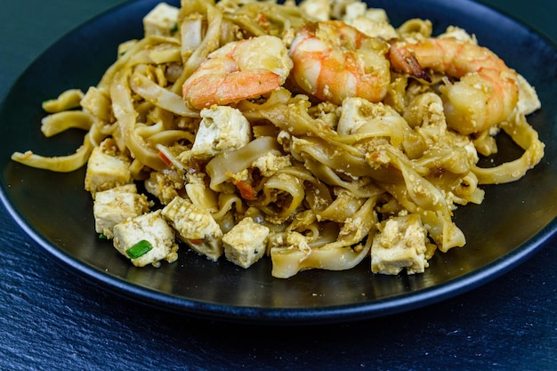 Black plate with pad thai on a slate board