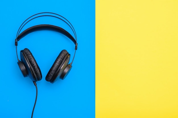 Black professional earphones with wire on blue and yellow.