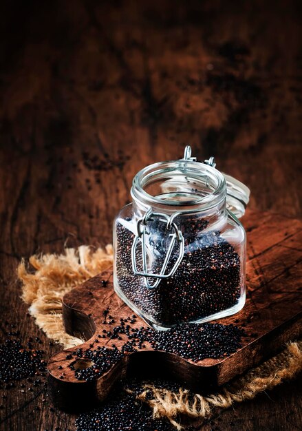 Black quinoa seeds in glass jar vintage kitchen table background selective focus