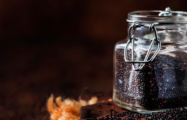 Black quinoa seeds in glass jar vintage kitchen table background selective focus