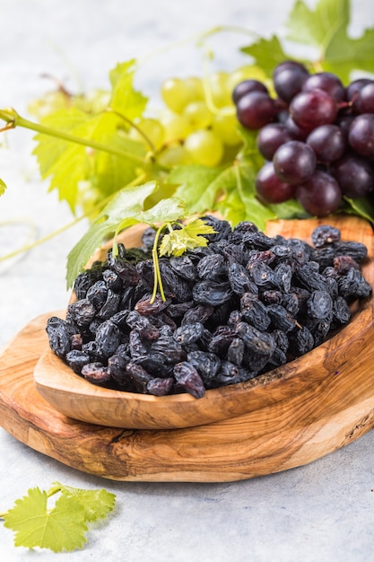 Black raisins in bowl on stone background