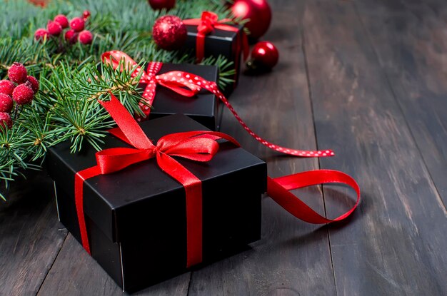 Black and red christmas gift box with red ribbon and fir branches