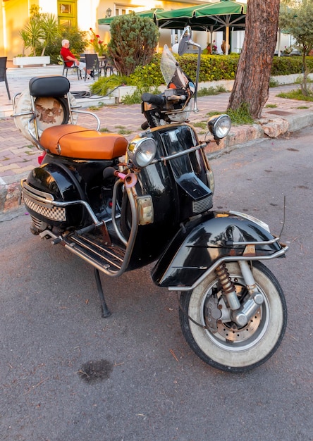 Black Retro scooter Vespa in the street  in Greece