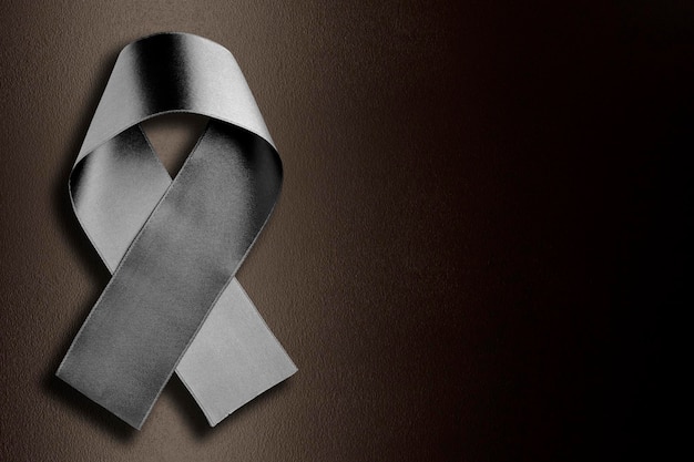 black ribbon symbolizing mourning on black illuminated background