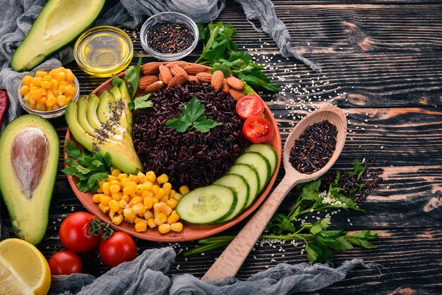 Black rice avocado cucumber corn and almonds On a wooden background Top view Free space for your text