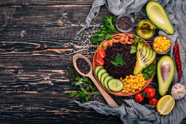 Black rice avocado cucumber corn and almonds On a wooden background Top view Free space for your text