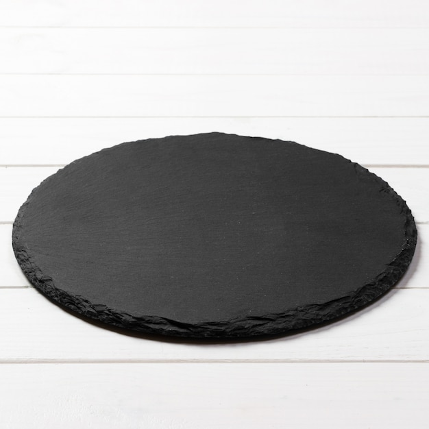 Black round plate on wooden , top view, copy space