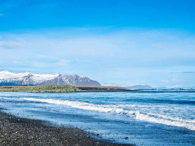 Black sand diamond beach with wave and snow mountains in Iceland