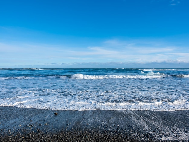 Black sand diamond beach with wave and snow mountains in Iceland