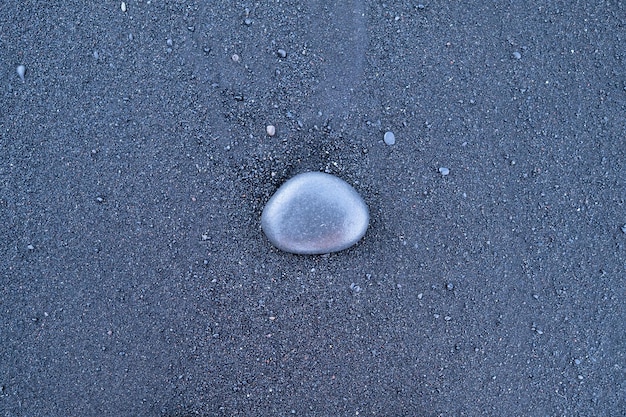 Black sand and pebble as a background Round stones on the beach Photography for design Textures in nature