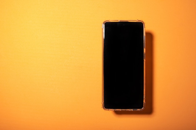  black screen phone on an orange EVA surface and hard light, top view