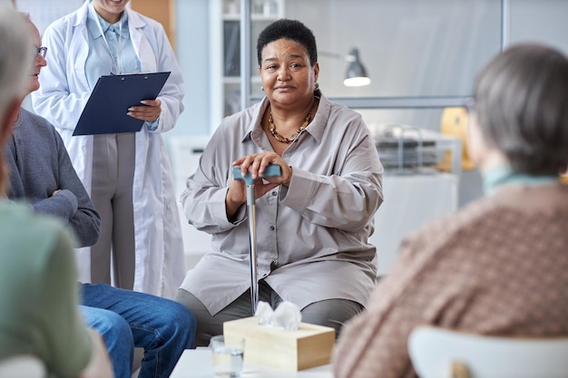 Black senior woman sharing with mental health support group in retirement home