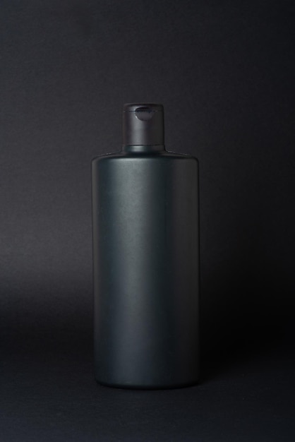 Black shampoo bottle on black background