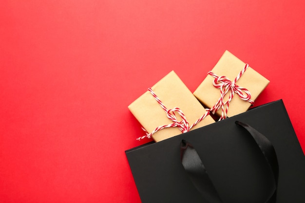 Black shopping bag with gifts on a red .