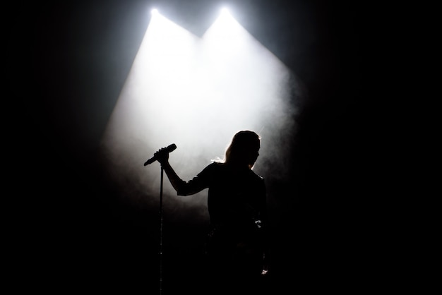 Black silhouette of female singer with white spotlights