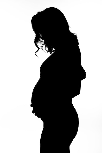 Black silhouette of a young pregnant woman on a white isolated background Happiness in anticipation of a baby Vertical