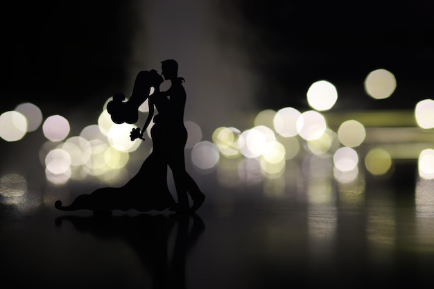 Black silhouettes of pair dancers performing Man and woman are dancing on gray background with white backlight Choreography New Year's ball