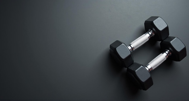 a black and silver dumbbell is resting on a black surface