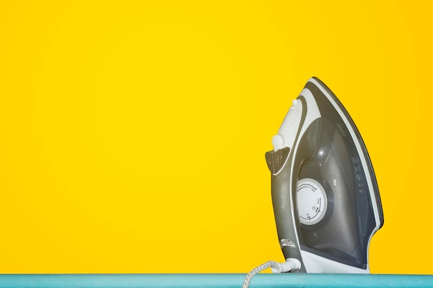 A black and silver iron sits on a blue table.