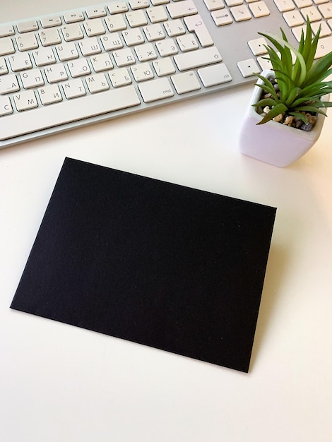 Black single envelope on a natural white table top view copy space